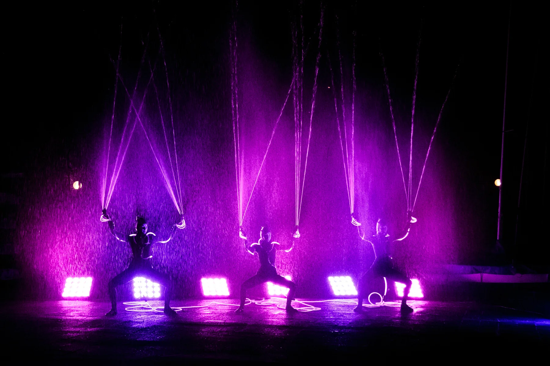 Tre artisti con getti d’acqua e luci scenografiche durante l’evento Maserati.